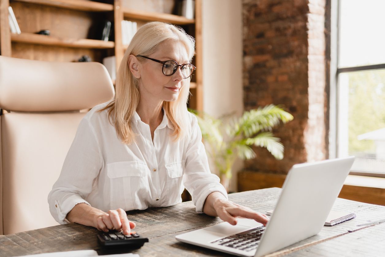 kobieta siedzi przy biurku, przed laptopem i oblicza wysokość zaliczki