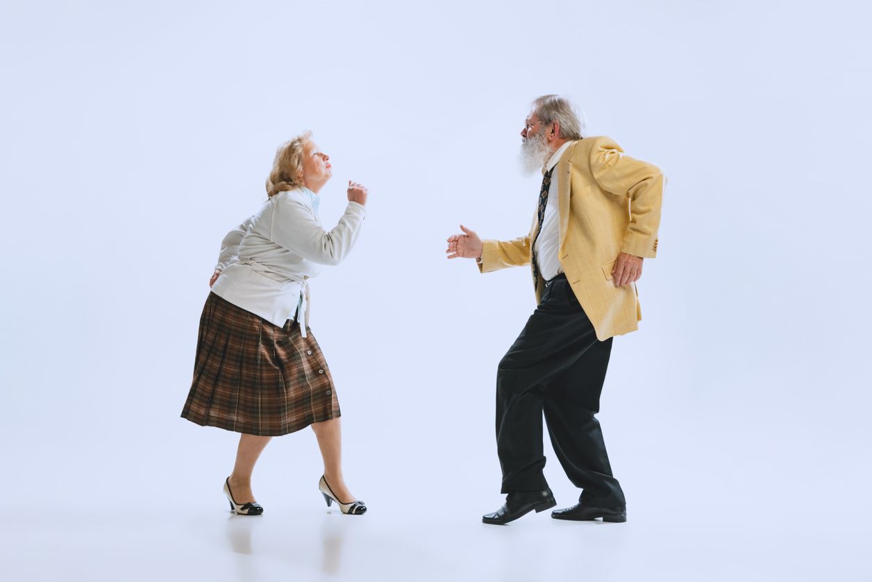 uśmiechnięci emeryci tańczą na pastelowym tle