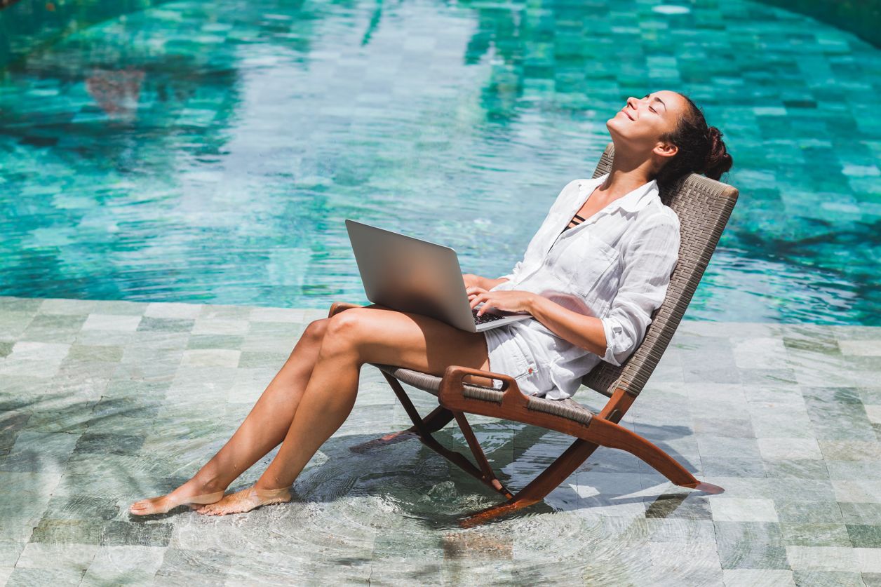 kobieta na leżaku nad basenem z laptopem na kolanach
