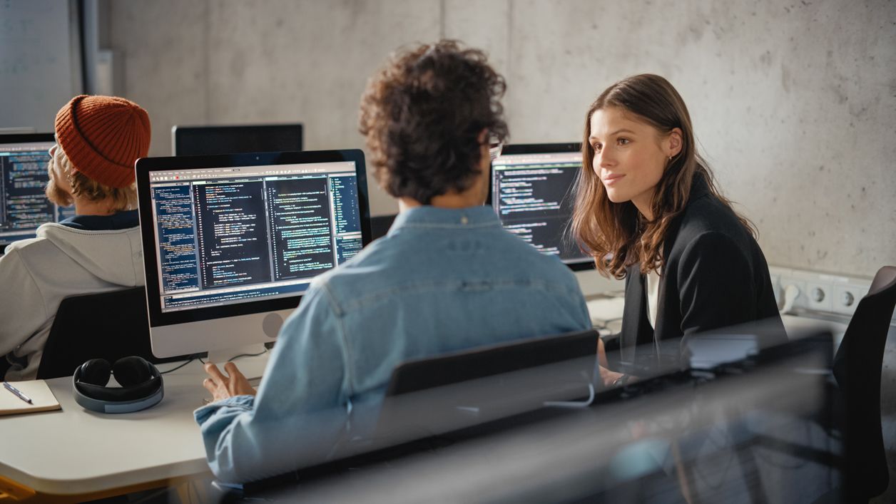 programiści siedzą przed monitorami i piszą kod