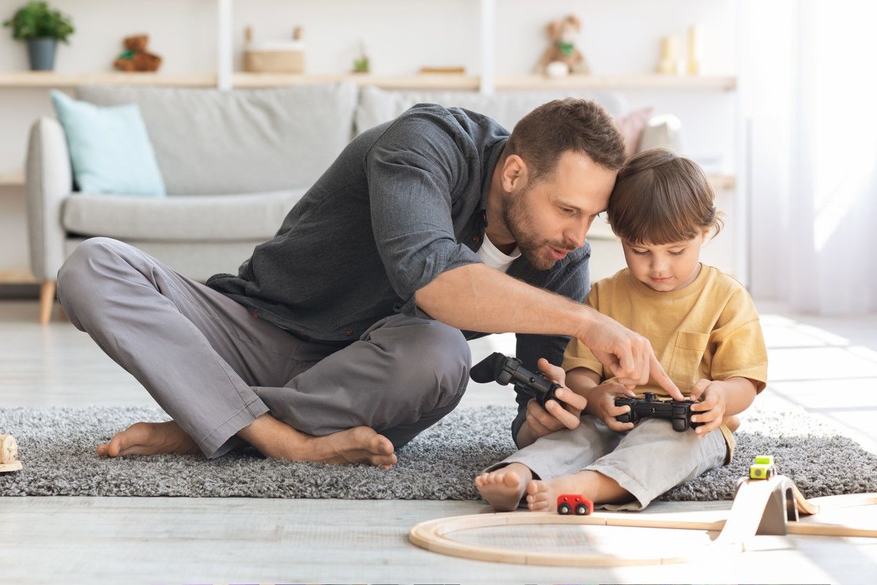 mężczyzna z chłopcem grają w grę i siedzą na dywanie