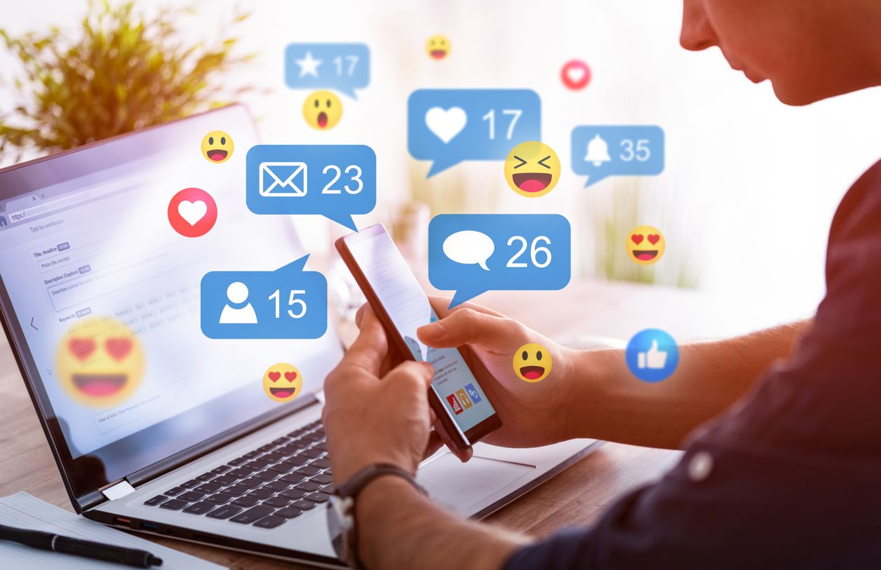 ikony reakcji w mediach społecznościowych nad laptop, przed którym siedzi mężczyzna