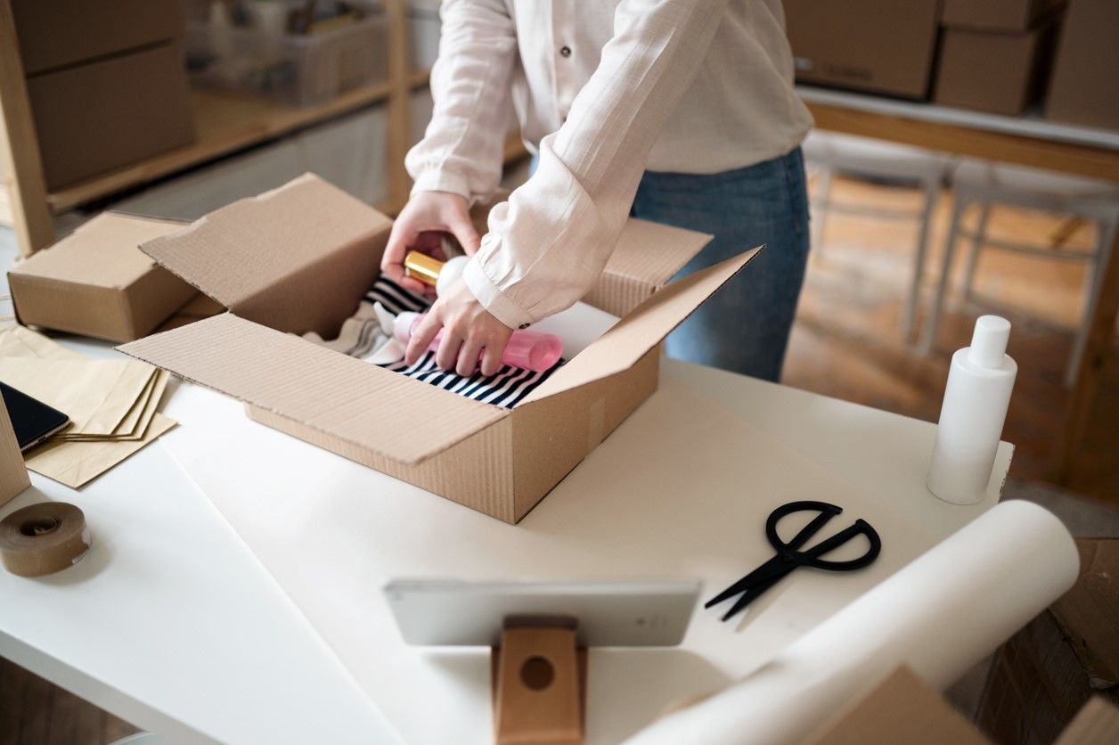 przedsiębiorczyni pakuje produkty zamówione przez klientów do paczki