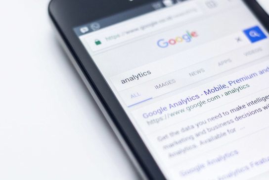 Telefon na stole z otwartą wyszukiwarką Google i hasłem Analytics