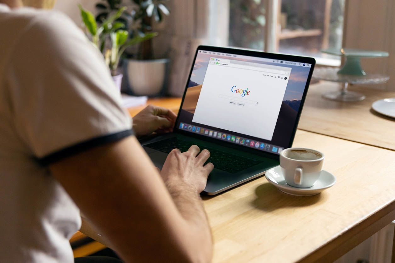Mężczyzna siedzi przed laptopem z włączoną stroną startową Google