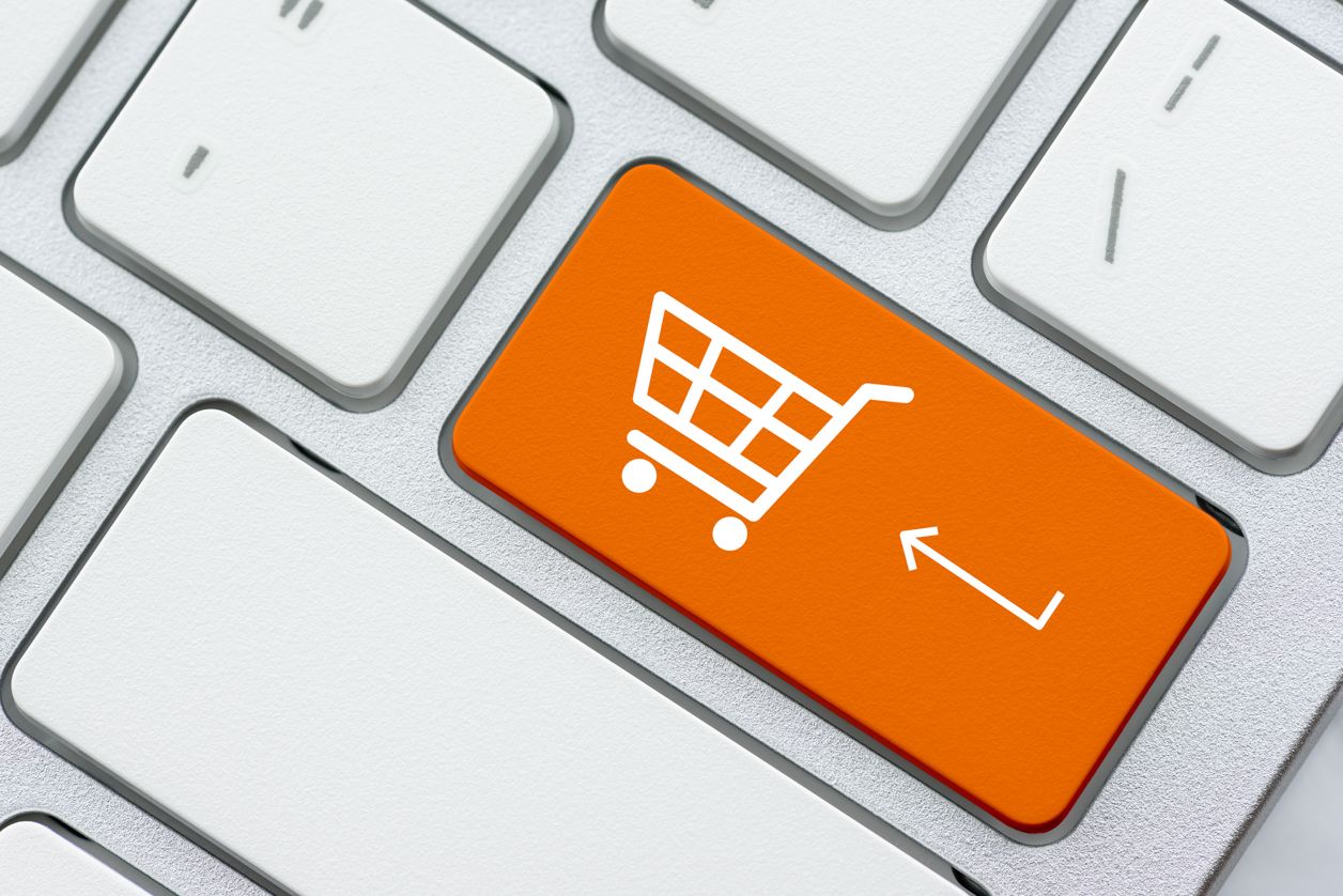 wózek zakupowy na pomarańczowym przycisku na klawiaturze, symbolizuje zakupy i płatności online