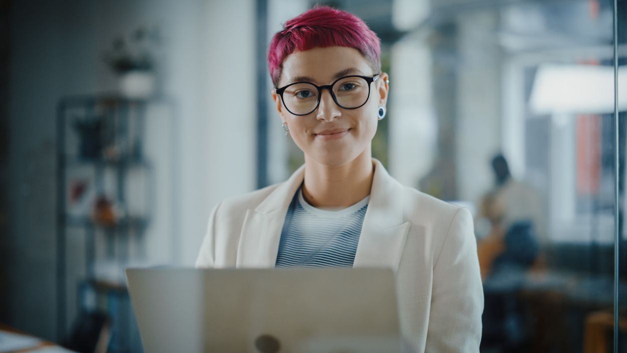 kobieta, przedsiębiorczyni siedzi przy laptopie i uśmiecha się