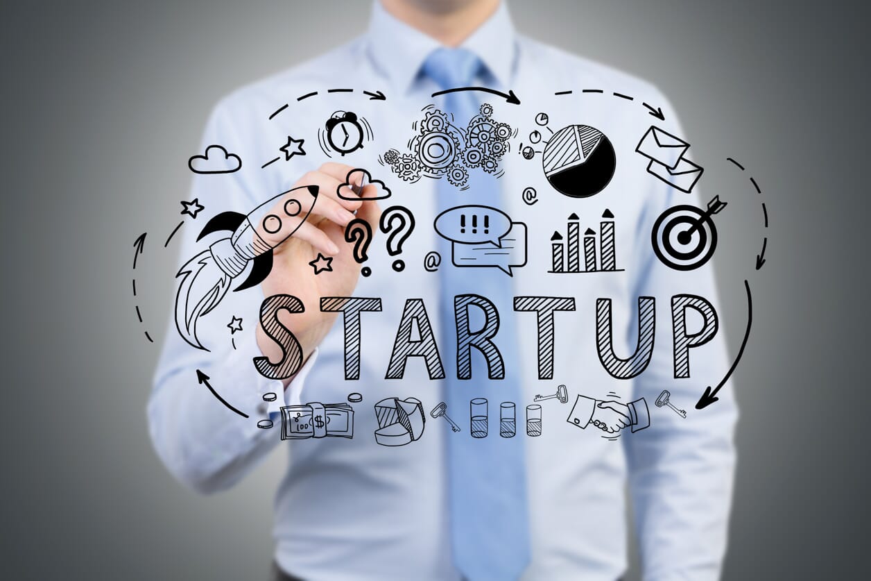 mężczyzna, przedsiębiorca tworzy na szybie grafikę z napisem start-up