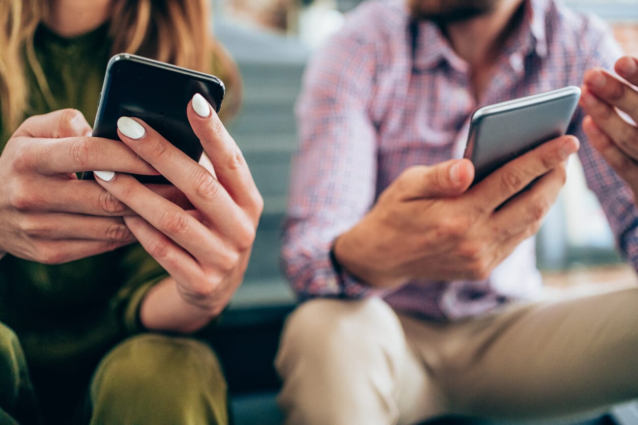 kobieta i mężczyzna patrzą na ekrany telefonów