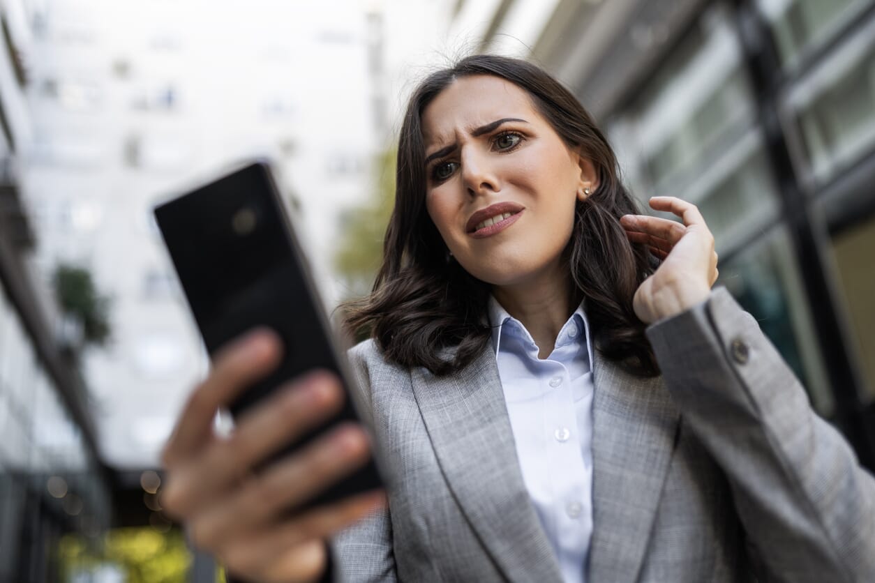 kobieta, przedsiębiorczyni patrzy na ekran telefonu ze zdziwieniem
