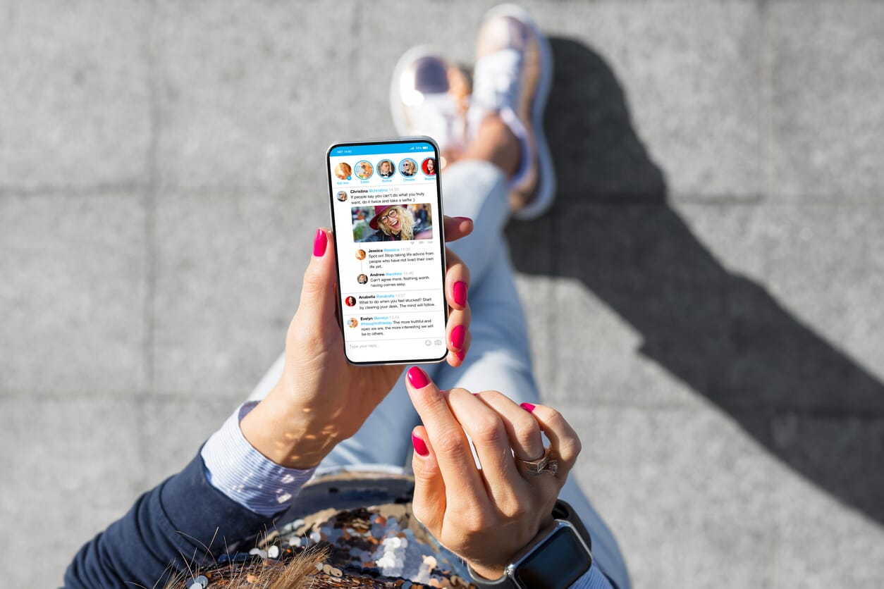 kobieta i trzyma smartphona, na ekranie widać social media