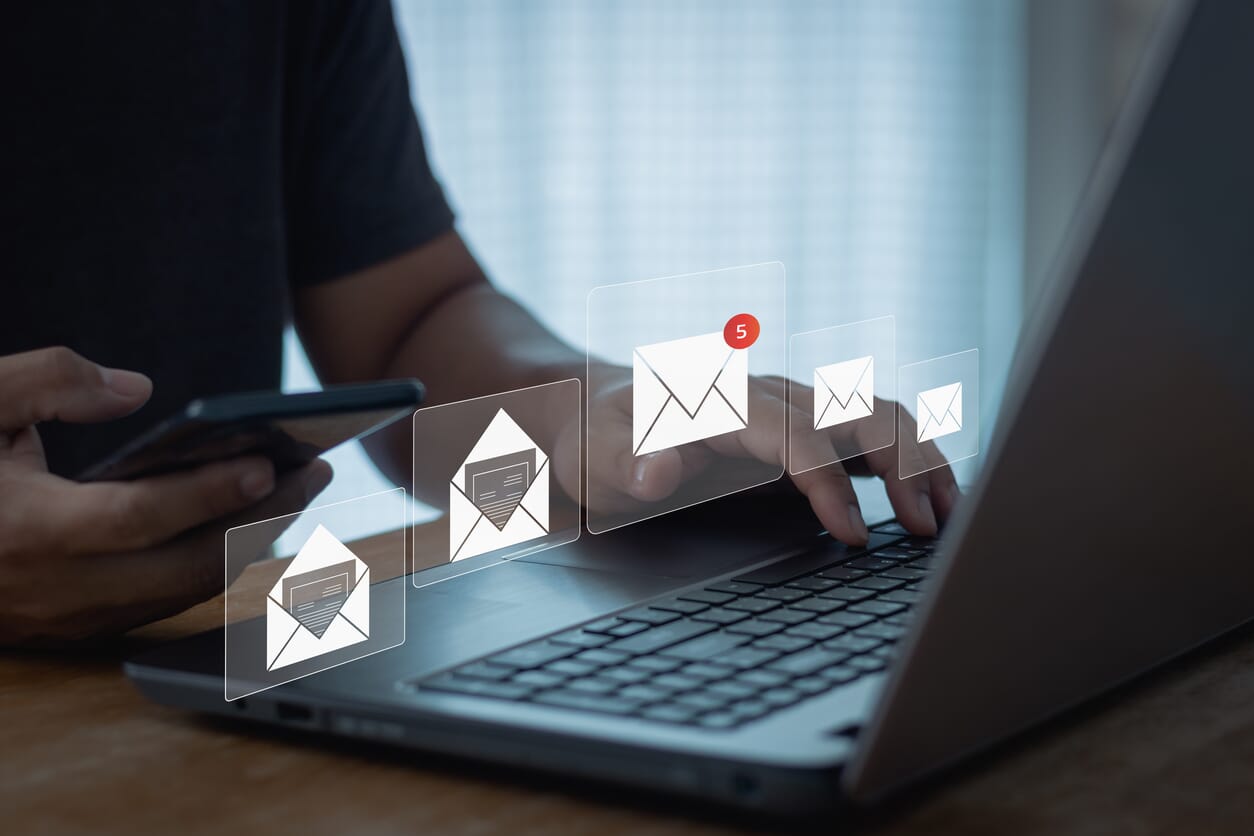przedsiębiorca z telefonem w ręce przed komputerem i ikony wiadomości email